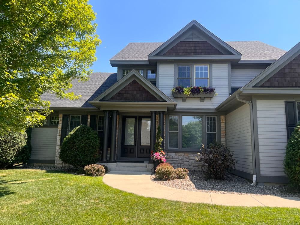 Modern two-story house with stone accents, landscaped yard, and flower box under windows.