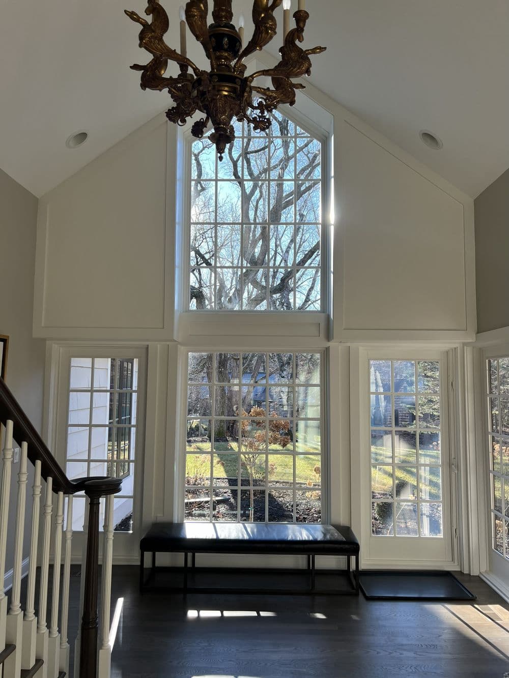 Spacious foyer with large windows, chandelier, and modern decor, showcasing natural light.