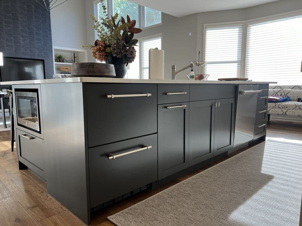 Modern kitchen island with black cabinetry, stainless steel appliances, and floral centerpiece.