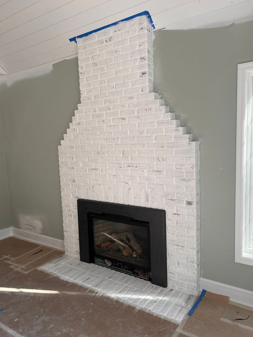 White brick fireplace with a modern design in an unfinished room.