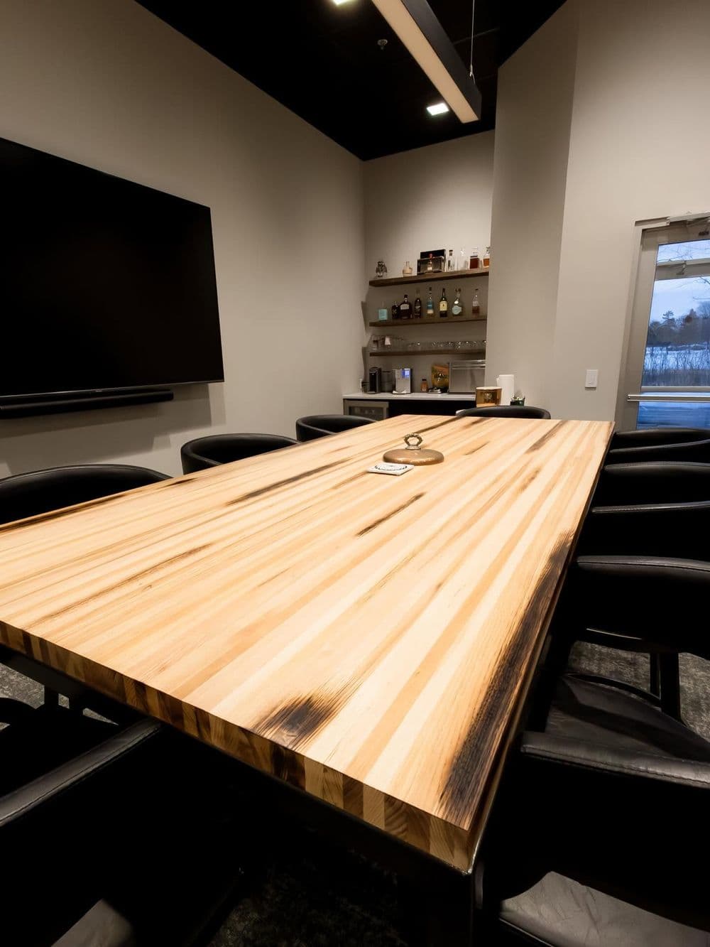 Modern conference room with a large wooden table and sleek black chairs.