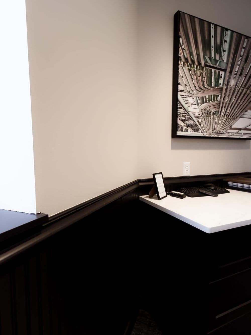 Modern office corner featuring sleek black cabinetry and artistic ceiling design.