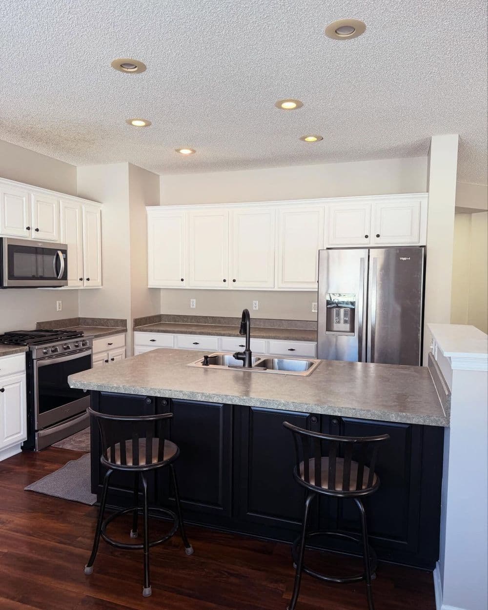 Modern kitchen with white cabinetry, stainless steel appliances, and an island with seating.