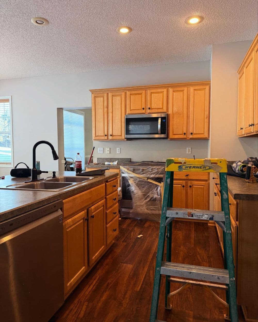 Modern kitchen with wooden cabinets, stainless steel appliances, and a ladder for upgrades.