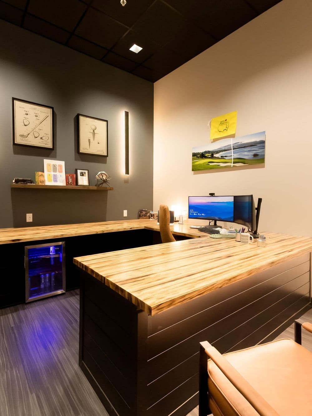 Modern office interior with a wooden desk, computer setup, and stylish decor.
