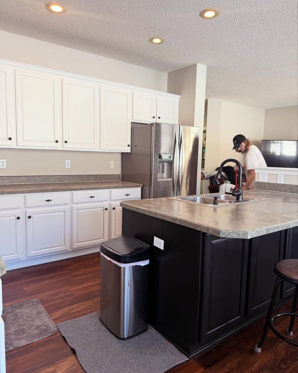 Modern kitchen featuring white cabinets, stainless steel appliances, and dark island counter.