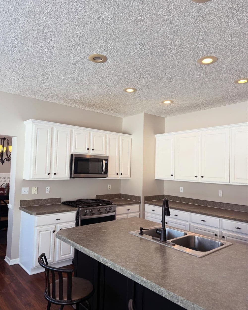 Modern kitchen with white cabinetry, granite countertops, and stainless steel appliances.